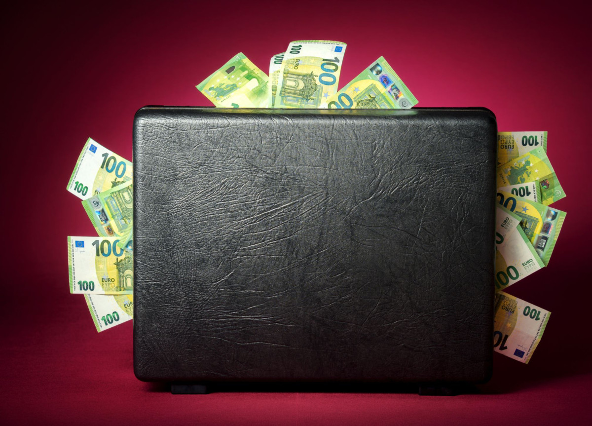 Ein Koffer aus dem zahlreiche 100-Euro-Scheine herausschauen