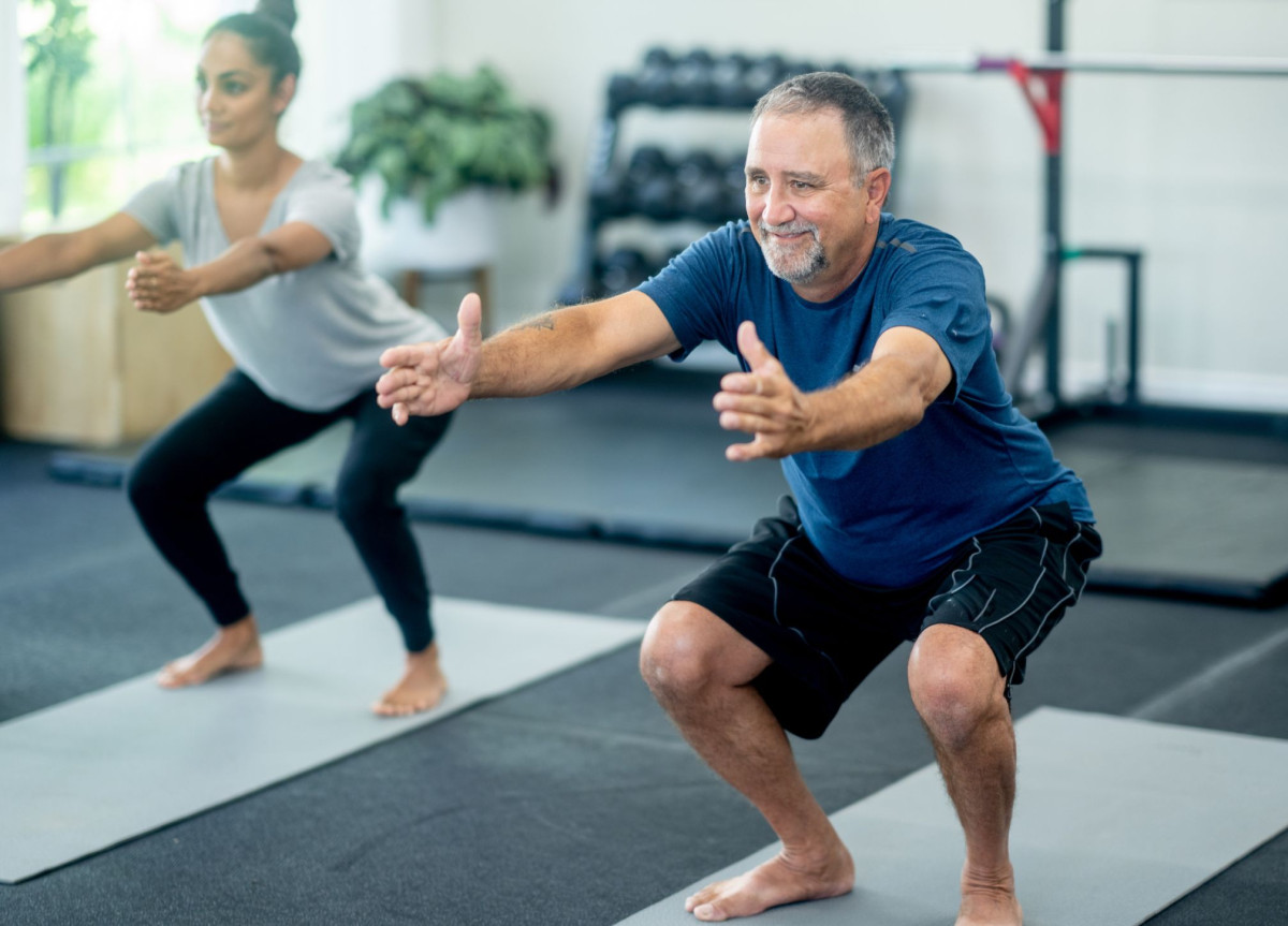 Ein Mann geht in einem Sportkurs in die Hocke