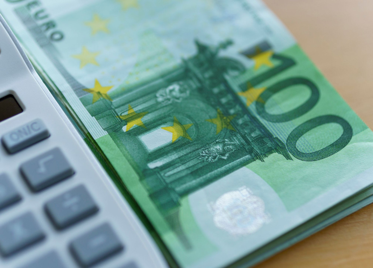 Ein Bündel 100-Euro-Scheine liegt neben einem Taschenrechner